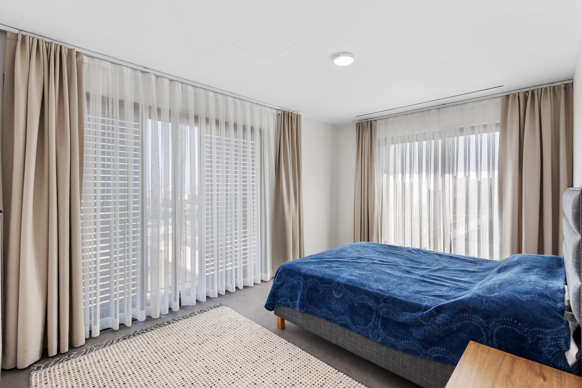 Master bedroom with sheer curtains and full-height window