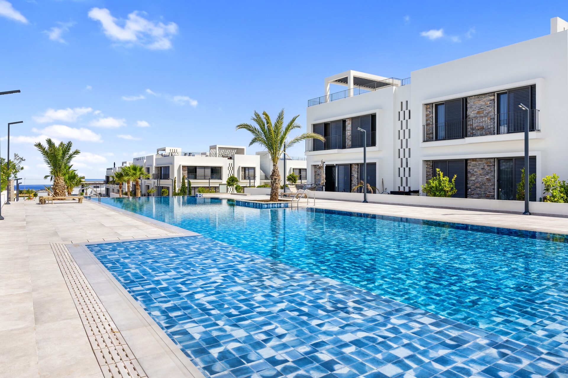 Mediterra · ground-level pool with palms and Mediterranean sea view